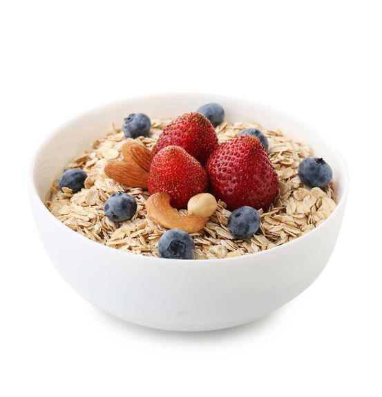 Oat flakes in bowl with berries and nuts isolated on white
